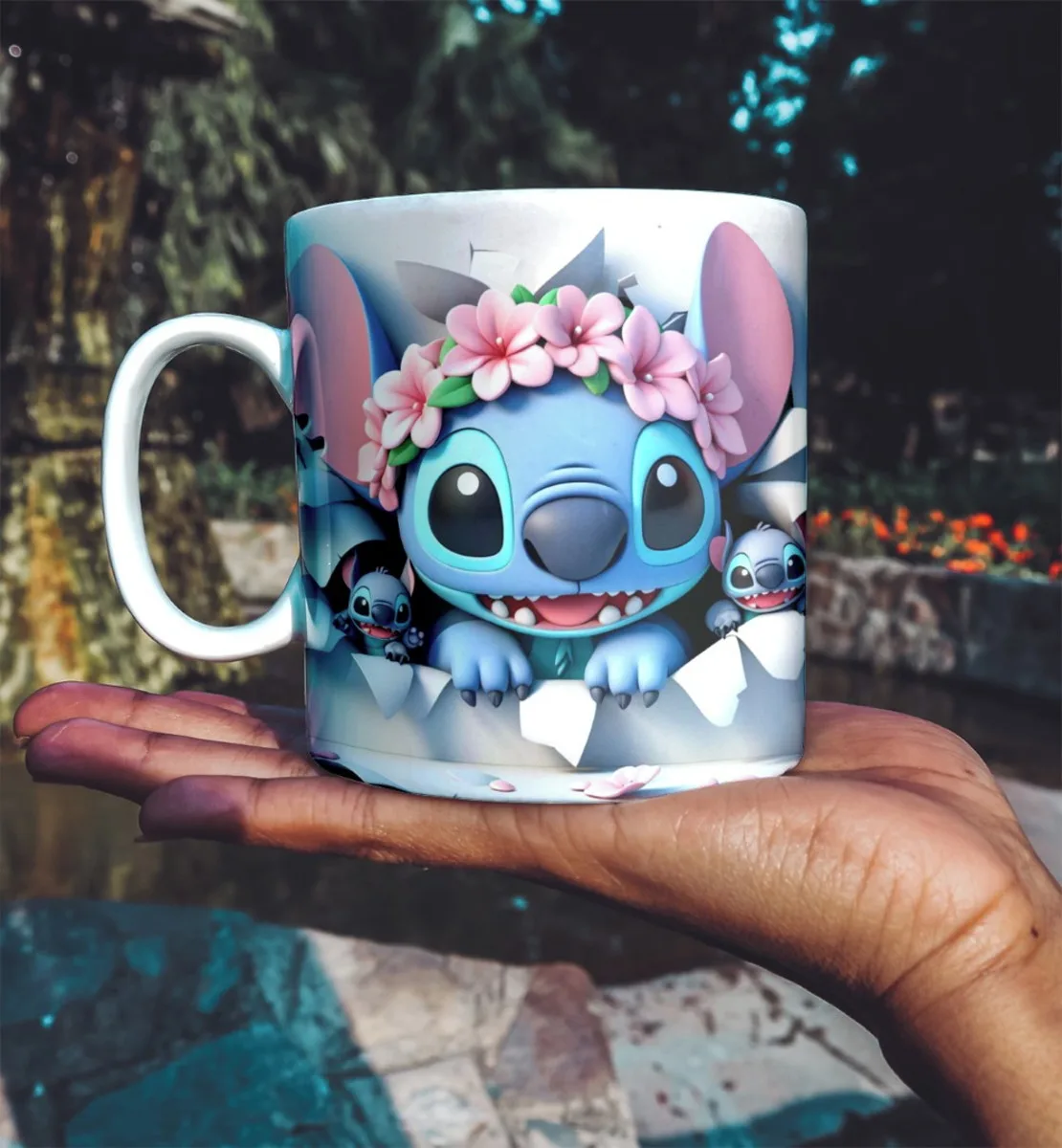 Mão segurando caneca branca decorada com personagem azul e flores rosas.