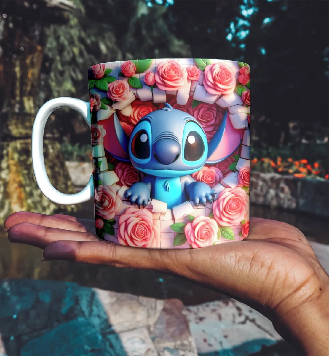 Mão segurando uma caneca estampada com criatura azul entre rosas cor de rosa.