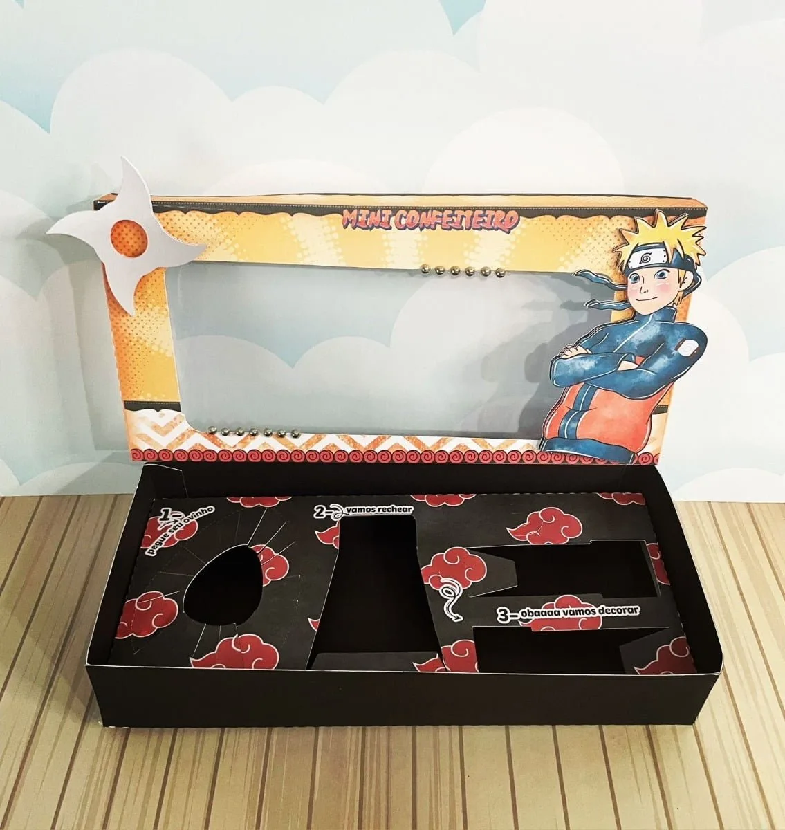 Arquivos De Corte Páscoa Naruto Mini Confeiteiro 5 Caixa aberta sobre mesa de madeira com personagem de anime e nuvens vermelhas