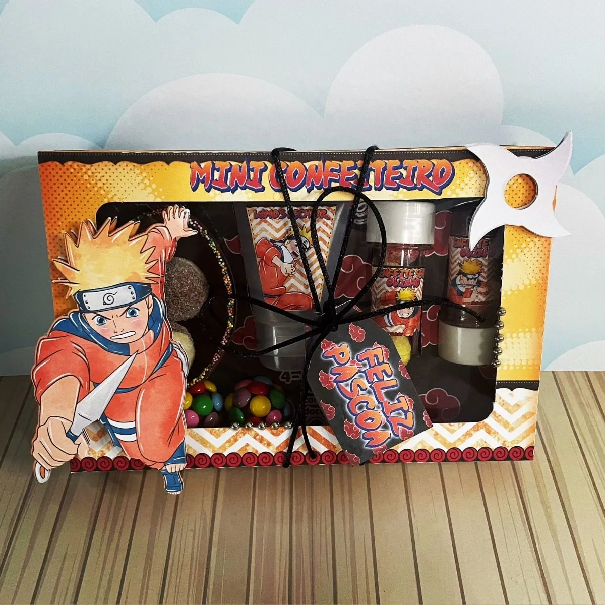 Arquivos De Corte Páscoa Naruto Mini Confeiteiro 8 Caixa decorada com tema de anime contendo doces confeitos e fitas pretas.
