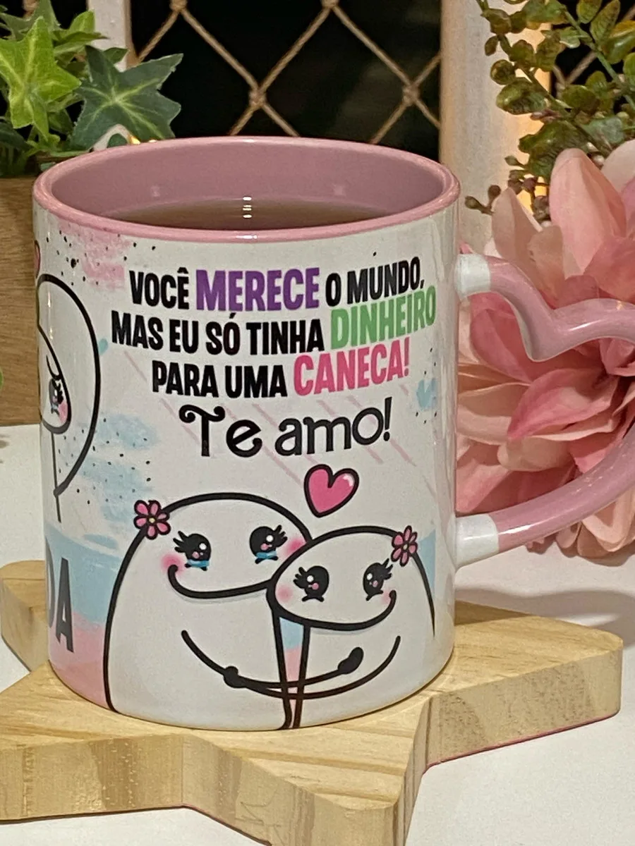 Caneca branca estampada com desenho de personagens e frase em português.