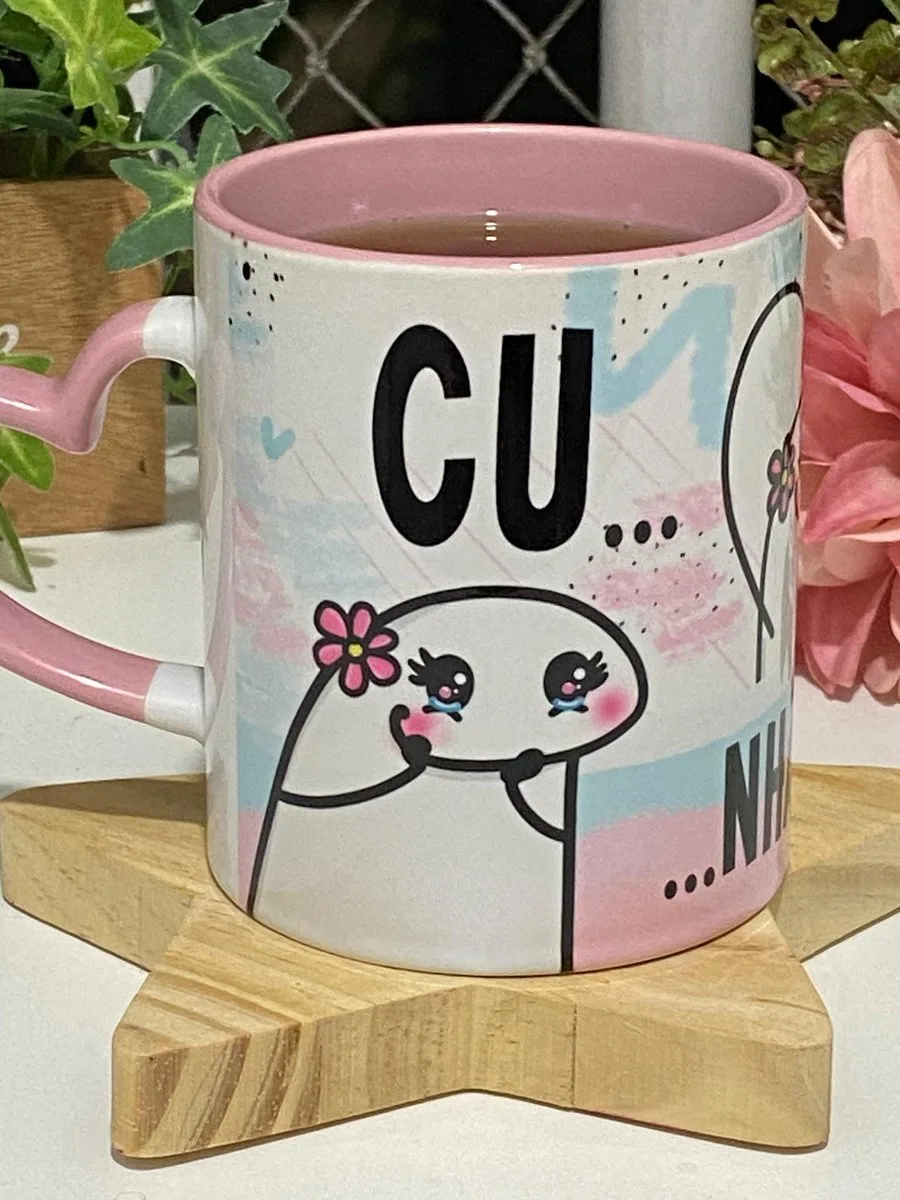 Caneca branca com estampa colorida apoiada sobre base de madeira em formato de estrela.