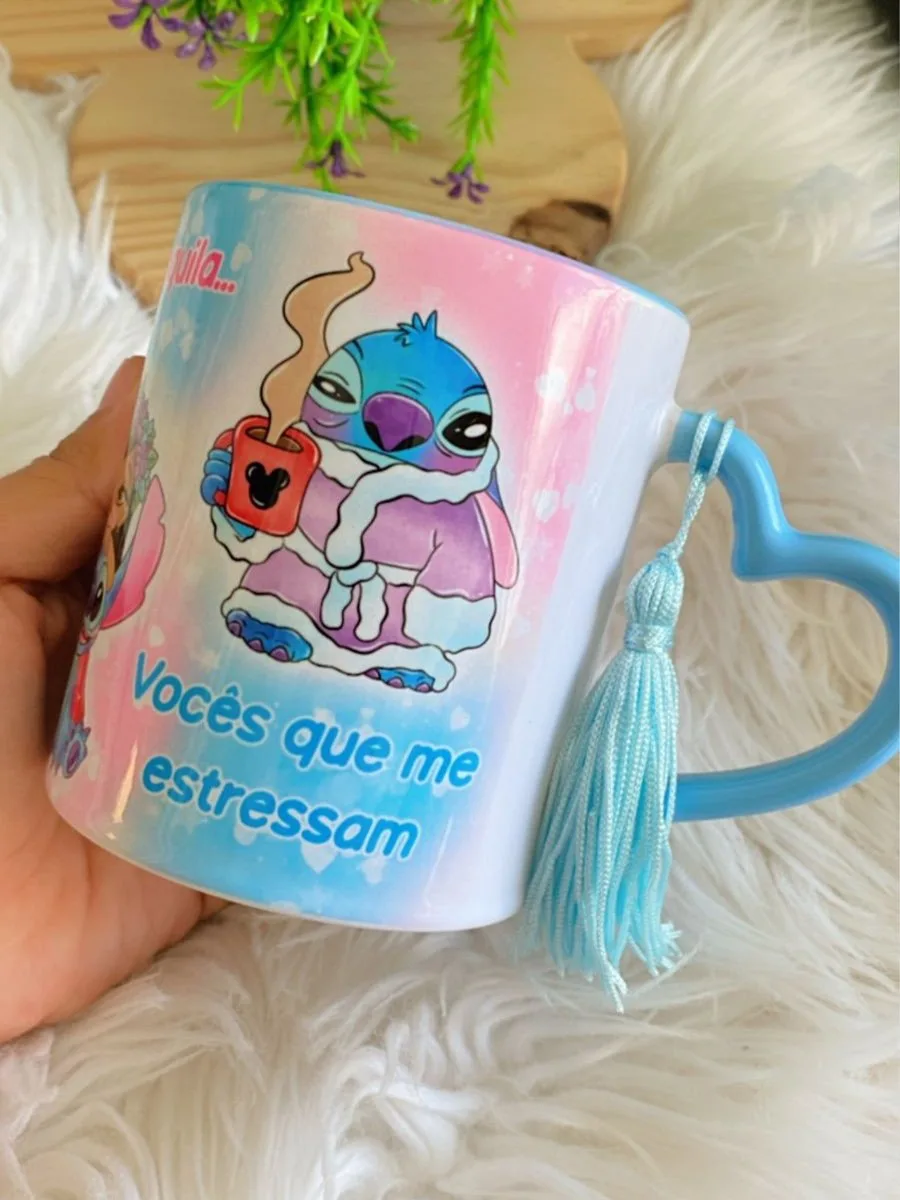 Arte Caneca Stitch Vocês Que Me Estressam 4 Caneca branca estampada com personagem azul segurando caneca vermelha sobre fundo rosa.