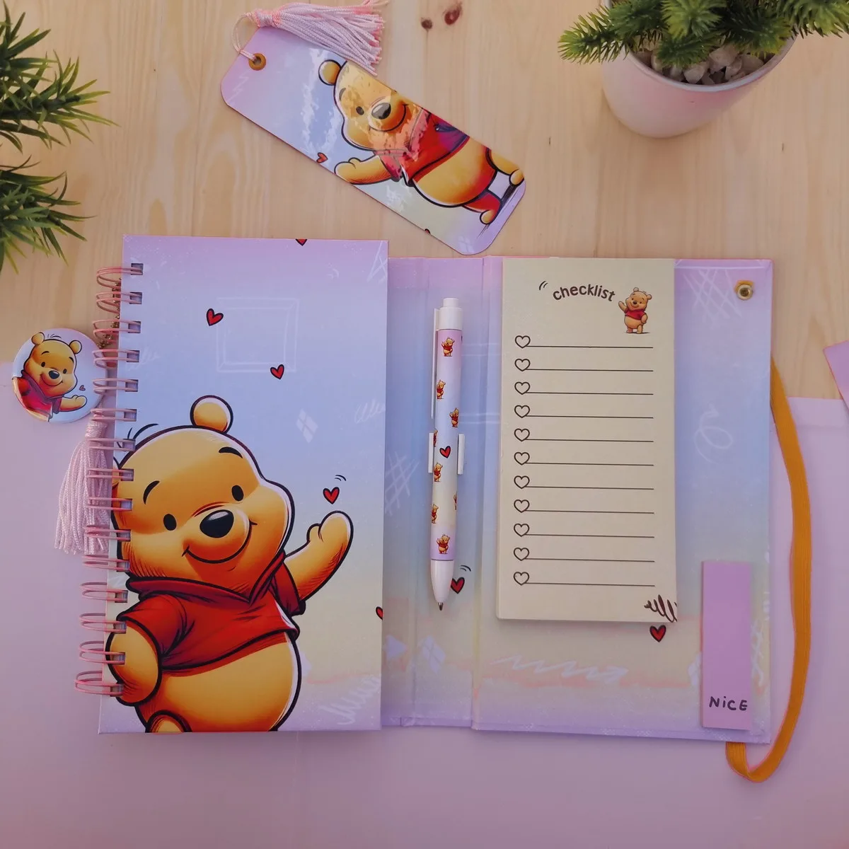Caderno espiral roxo decorado com urso amarelo, caneta, bloco de notas e marcador.