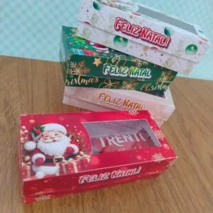 Caixinhas Natal - Png e pdf 9 Caixas de papel decoradas com temas natalinos e doces dentro sobre mesa de madeira