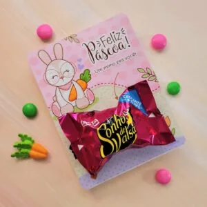 Cartão rosa de Páscoa com coelho, chocolate embalado e doces sortidos.