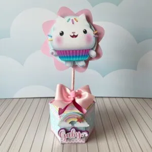 Centro de mesa infantil com desenho de gato sobre caixa decorada com arco-íris.