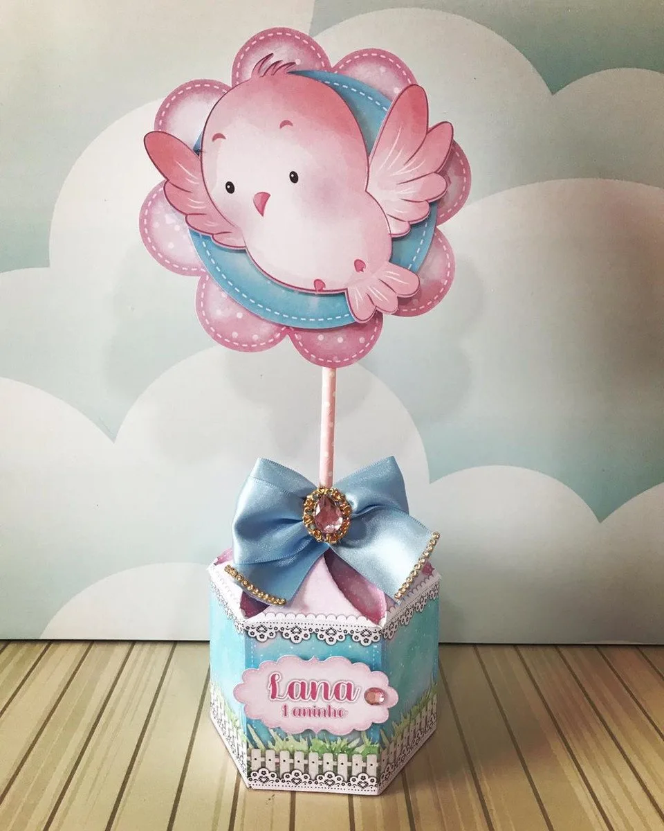Topo de bolo com passarinho rosa sobre base azul decorada com laço.