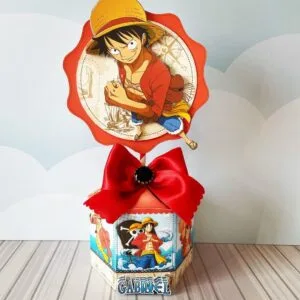 Topo de bolo temático com personagem de anime e laço vermelho grande em caixa decorada