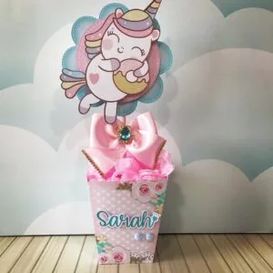 Topo de bolo de unicórnio rosa decorado com laço e flores de papel