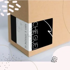 Caixa de papelão parda com adesivo personalizado contendo textos e ilustrações florais.