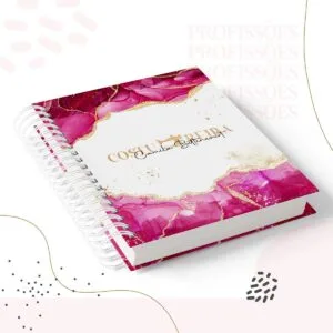 Caderno espiral com capa rosa e branca com detalhes dourados em fundo branco.