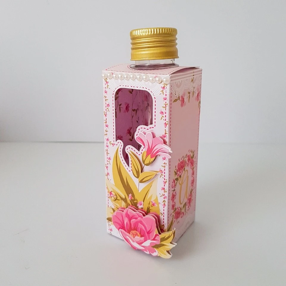 Kit Festa Floral Rosa 6 Caixa rosa decorada com flores 3D, janela e garrafa transparente. Fundo simples branco.