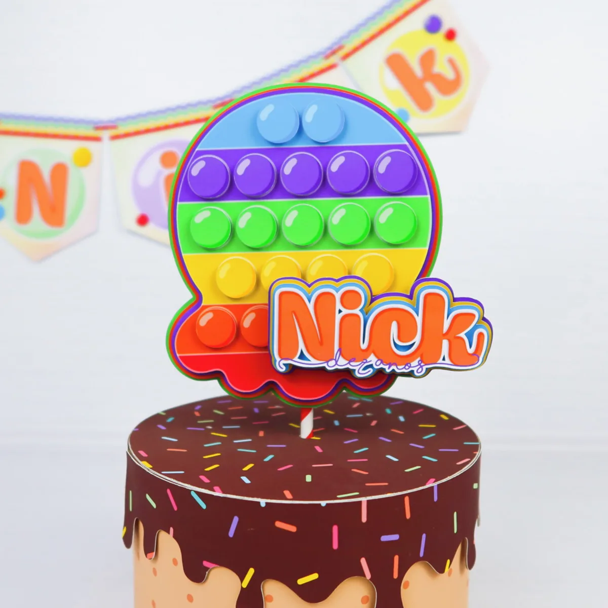 Topo de bolo circular colorido em formato de brinquedo sensorial com nome personalizado.