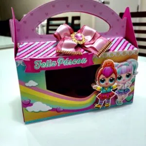Caixa de presente colorida com alça, laço rosa e desenhos infantis.