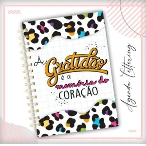 Capa de caderno com estampa de oncinha colorida e frase escrita à mão.