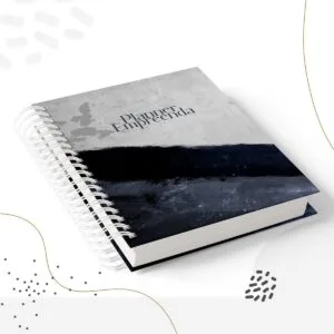 Caderno com capa espiralada cinza e preta sobre fundo branco abstrato.