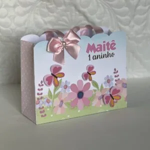 Sacolinha personalizada de papel com estampa de flores, borboletas e um laço rosa.