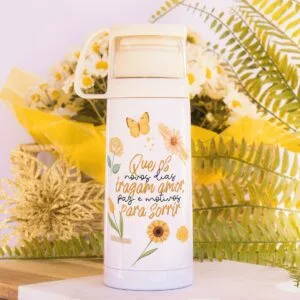 Garrafa térmica branca com estampa de flores amarelas e borboleta sobre fundo decorado.